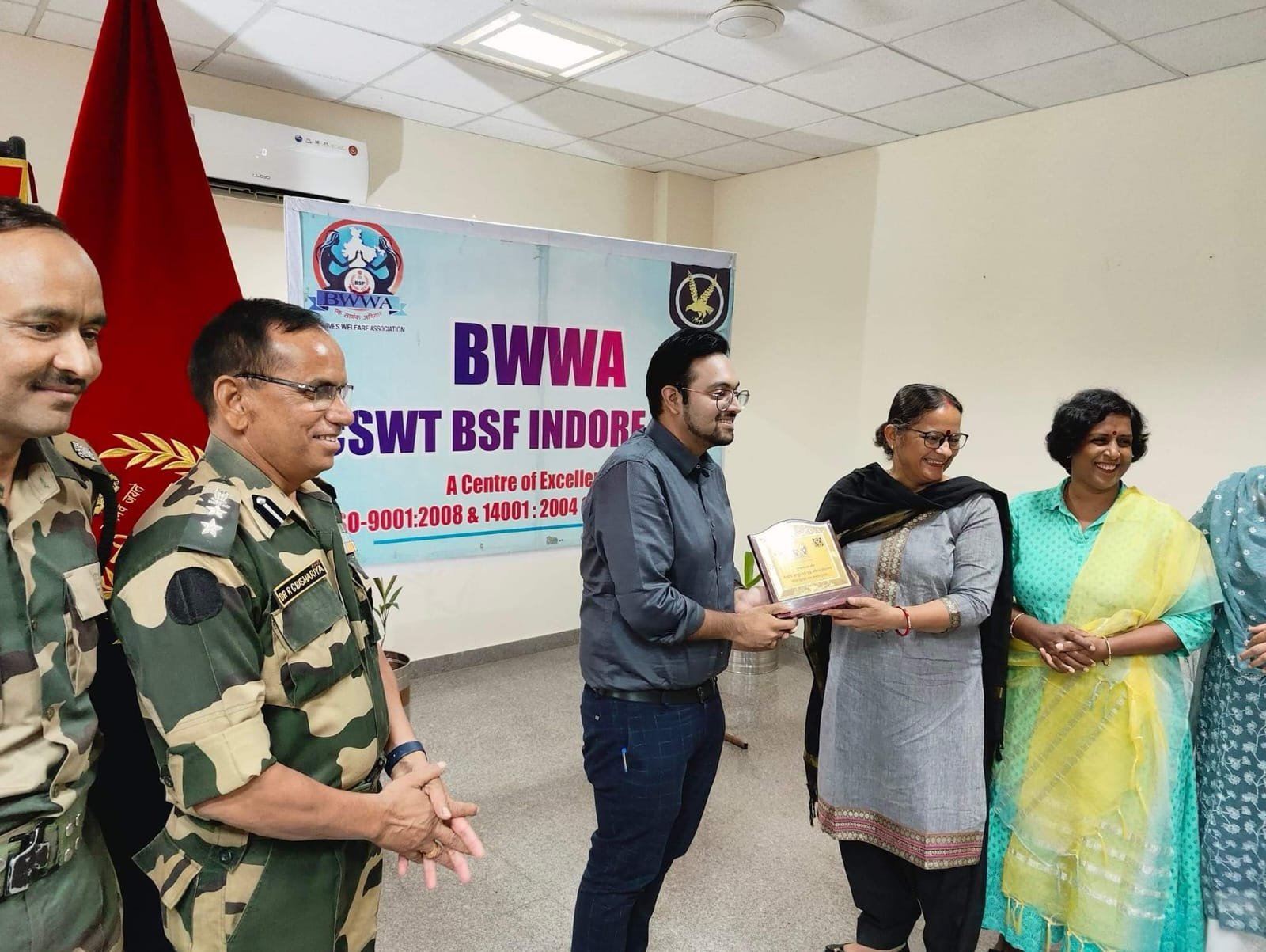 Dr. Varchasvi Mudgal receiving a plaque from a group of people at an event hosted by BSF.