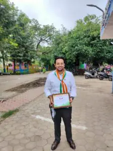 Dr. Varchasvi Mudgal with colleagues, receiving a document or gift in an office setting.