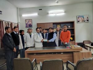 Dr. Varchasvi Mudgal receiving an award and certificate from two individuals in an office setting.
